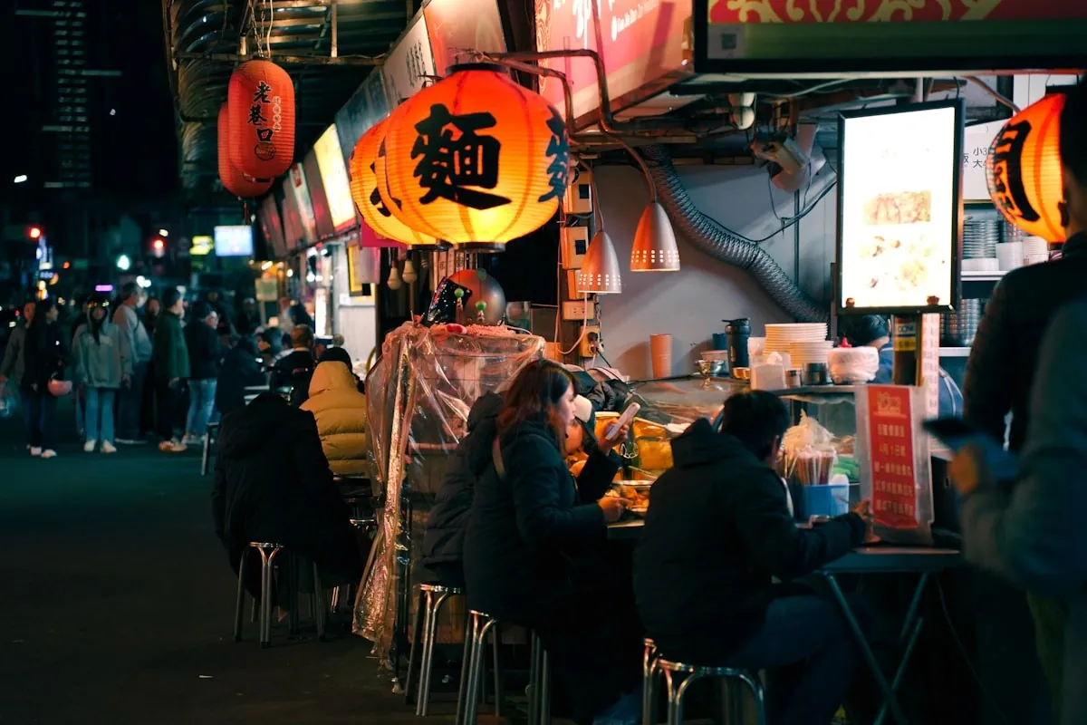 Diners gathered around a busy evening kitchen stall.