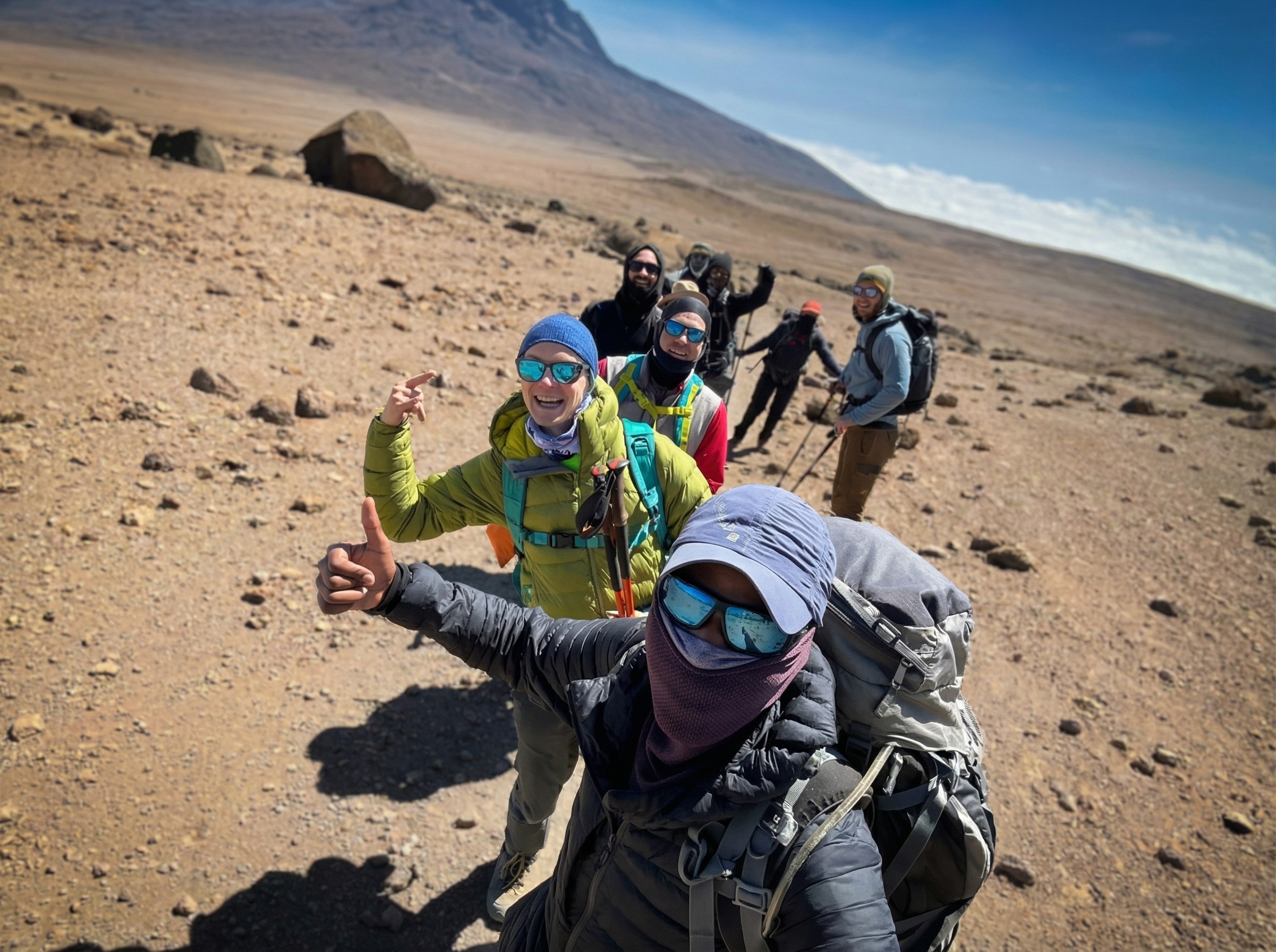 Smiling tour guides standing together in warm AlUla sunset light.