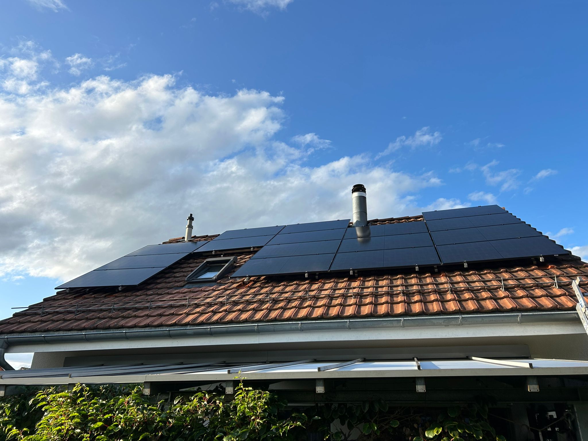 Moderne Solaranlage auf einem Ziegeldach unter blauem Himmel für optimierte Photovoltaik-Leistung.
