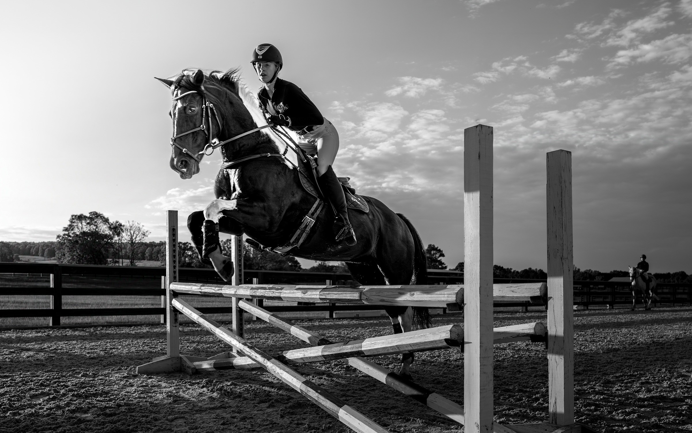 A female rider and her horse leap over a fence on the training course at Bright Farms.