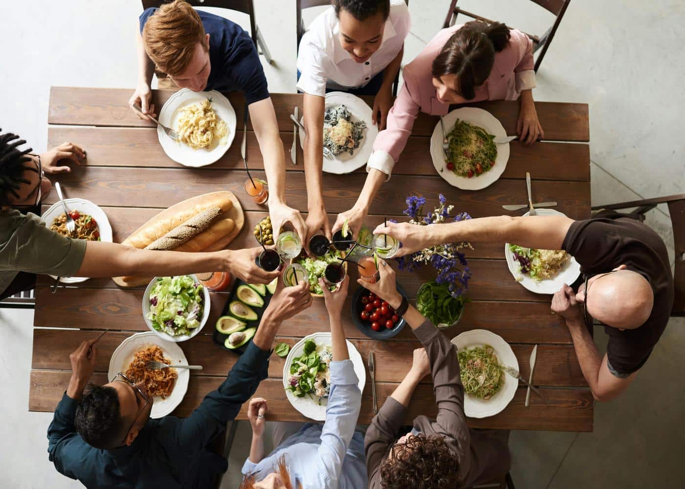 Group of people sitting around a table having a meal and toasting drinks