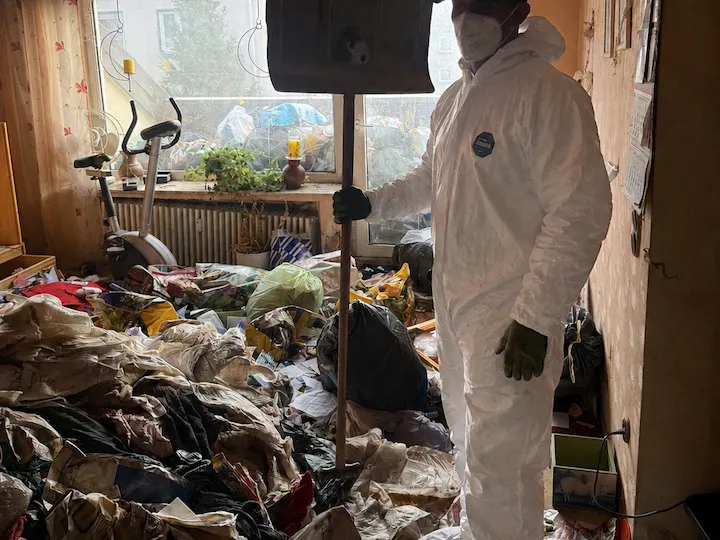 Mitarbeiter im Schutzanzug in einer stark vermüllten Messie-Wohnung