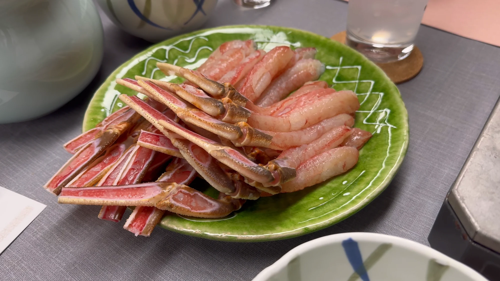 Raw snow crab legs arranged on a green plate in a Kinosaki restaurant.