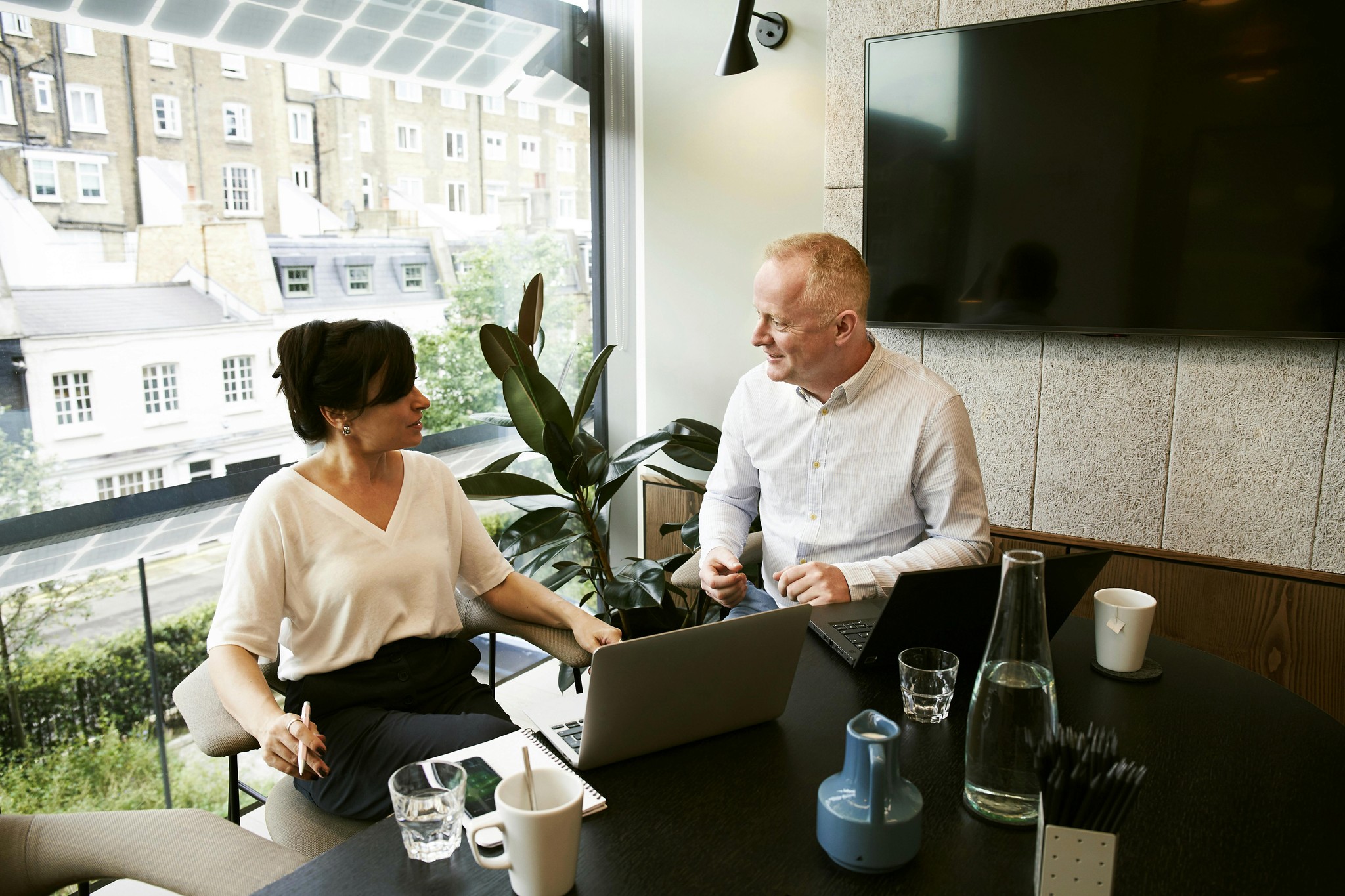 Two people sitting at a desk talking to each other