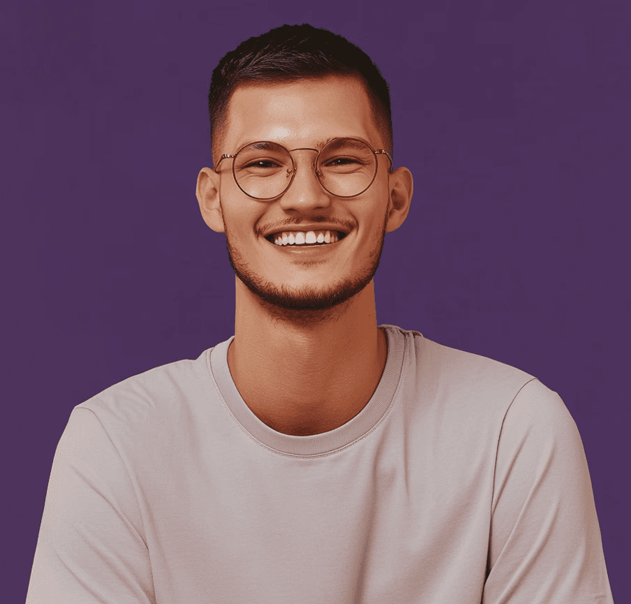 A smiling person with short dark hair, wearing round glasses and a beige T-shirt, stands against a purple background. The mood is cheerful and relaxed.