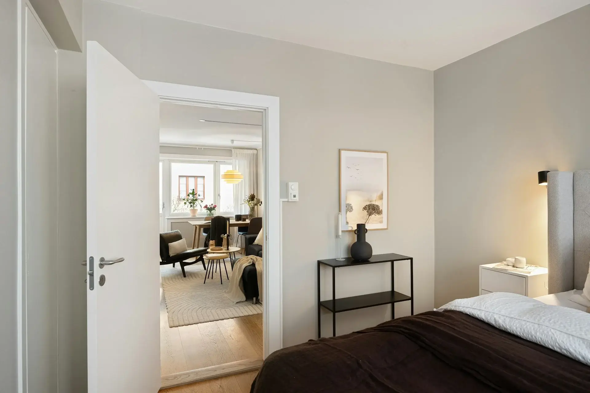 Bright bedroom with open door, neutral walls, and modern bedside decor.