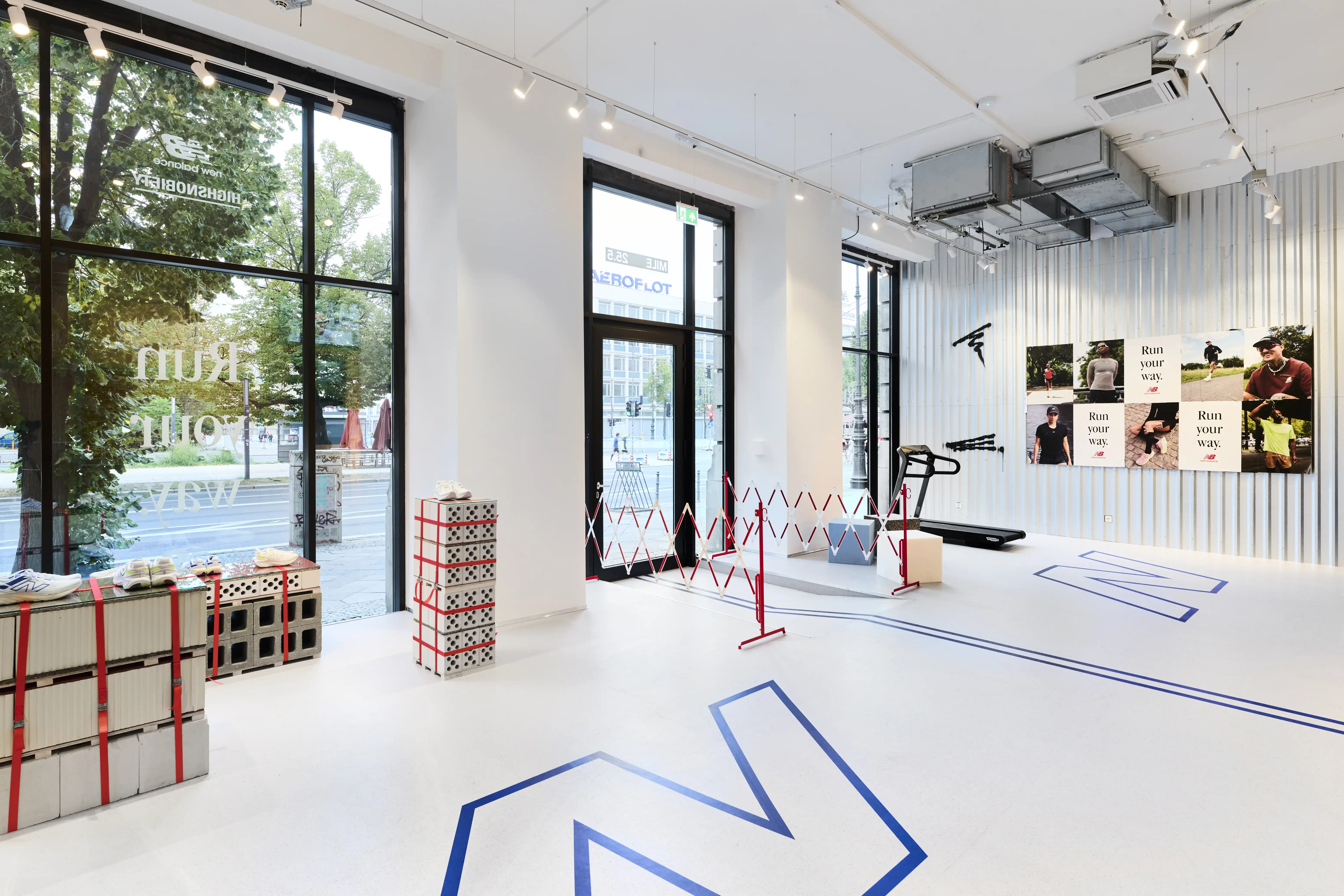 View through the Highsnobiety x New Balance pop-up with stacked crate displays, red-and-white barriers and Run Your Way posters.