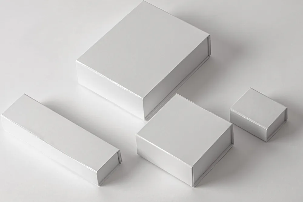 Magnetic box packaging mockup set featuring four black boxes of various sizes (big, large, square, and small) with bold white typography. Arranged on a gray surface with soft shadows for a minimalist presentation.