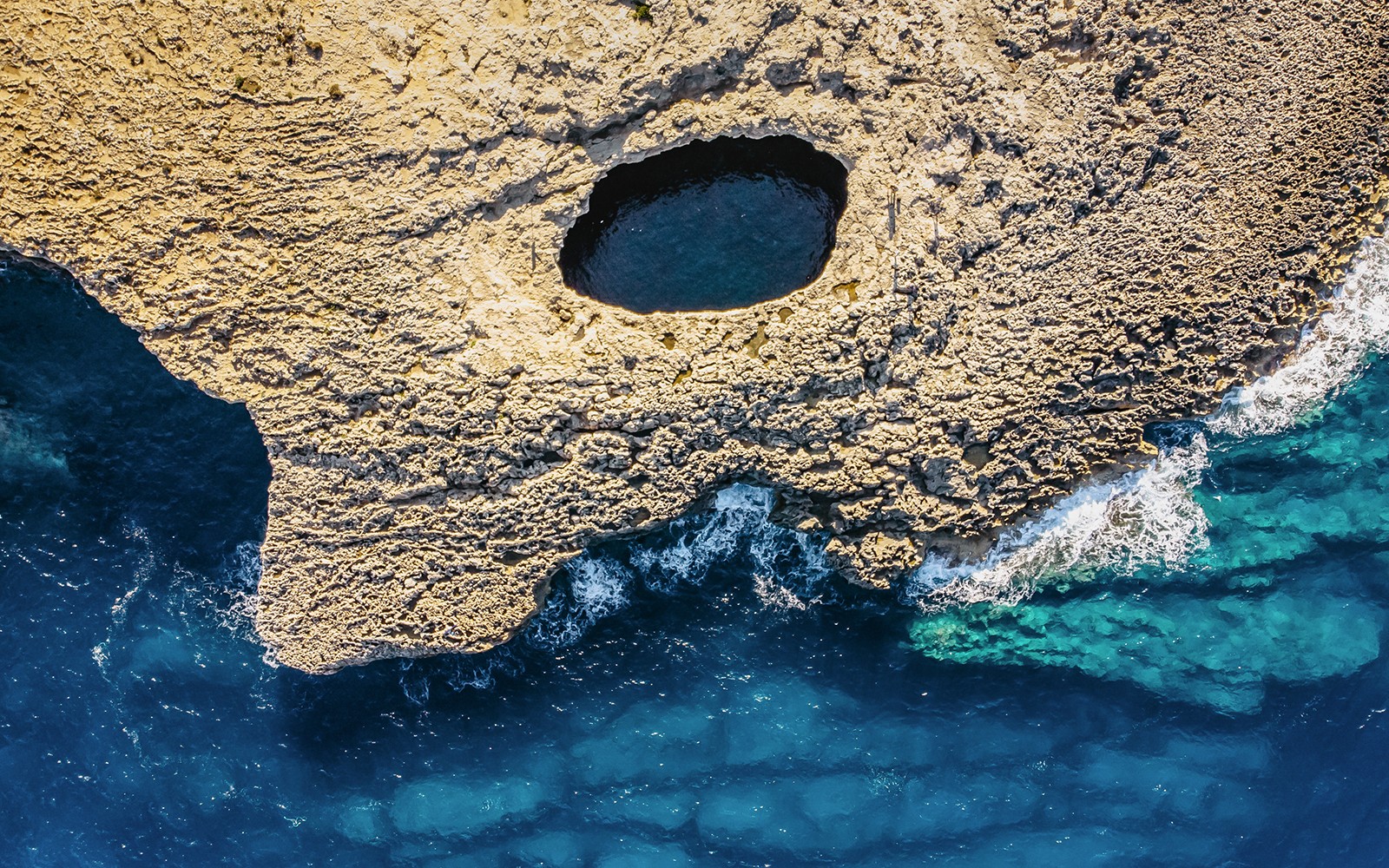 Aerial view of Ahrax fallen cave and Coral Lagoon, Malta with surrounding sea.