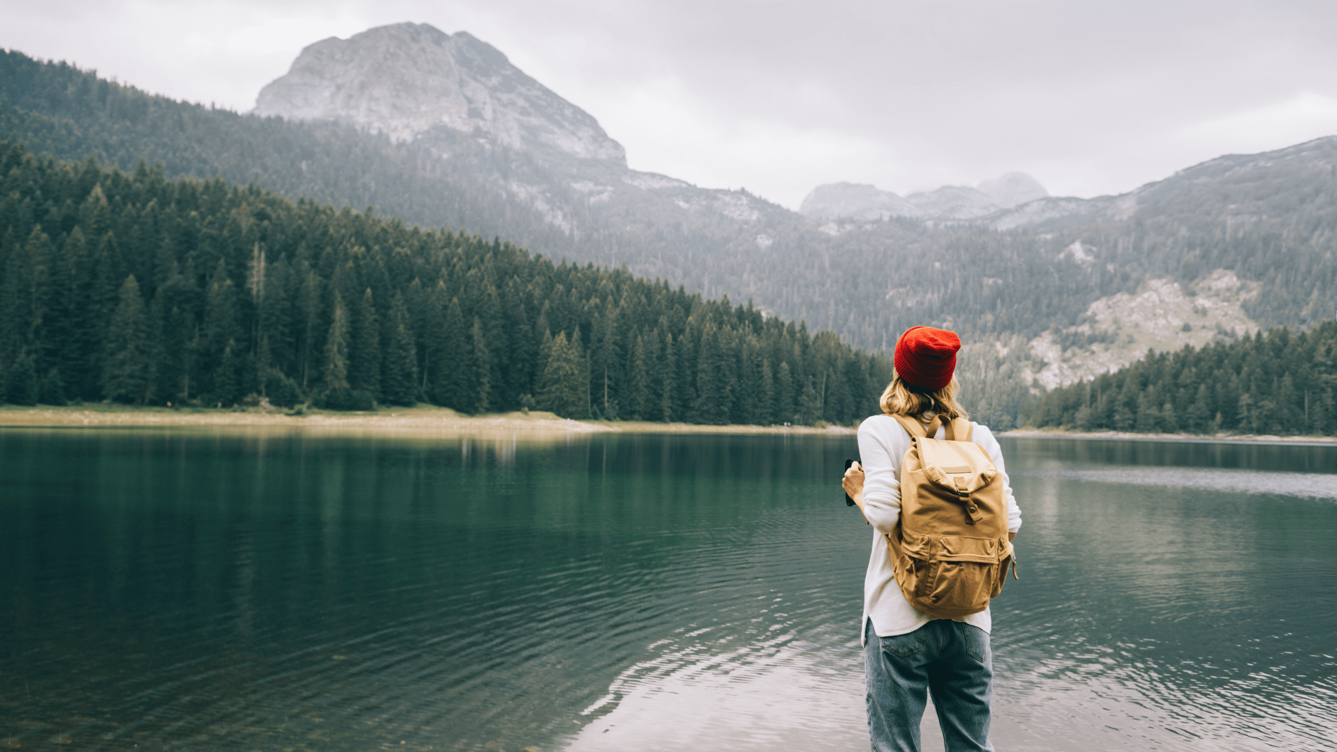 woman sitting on wood near body of water