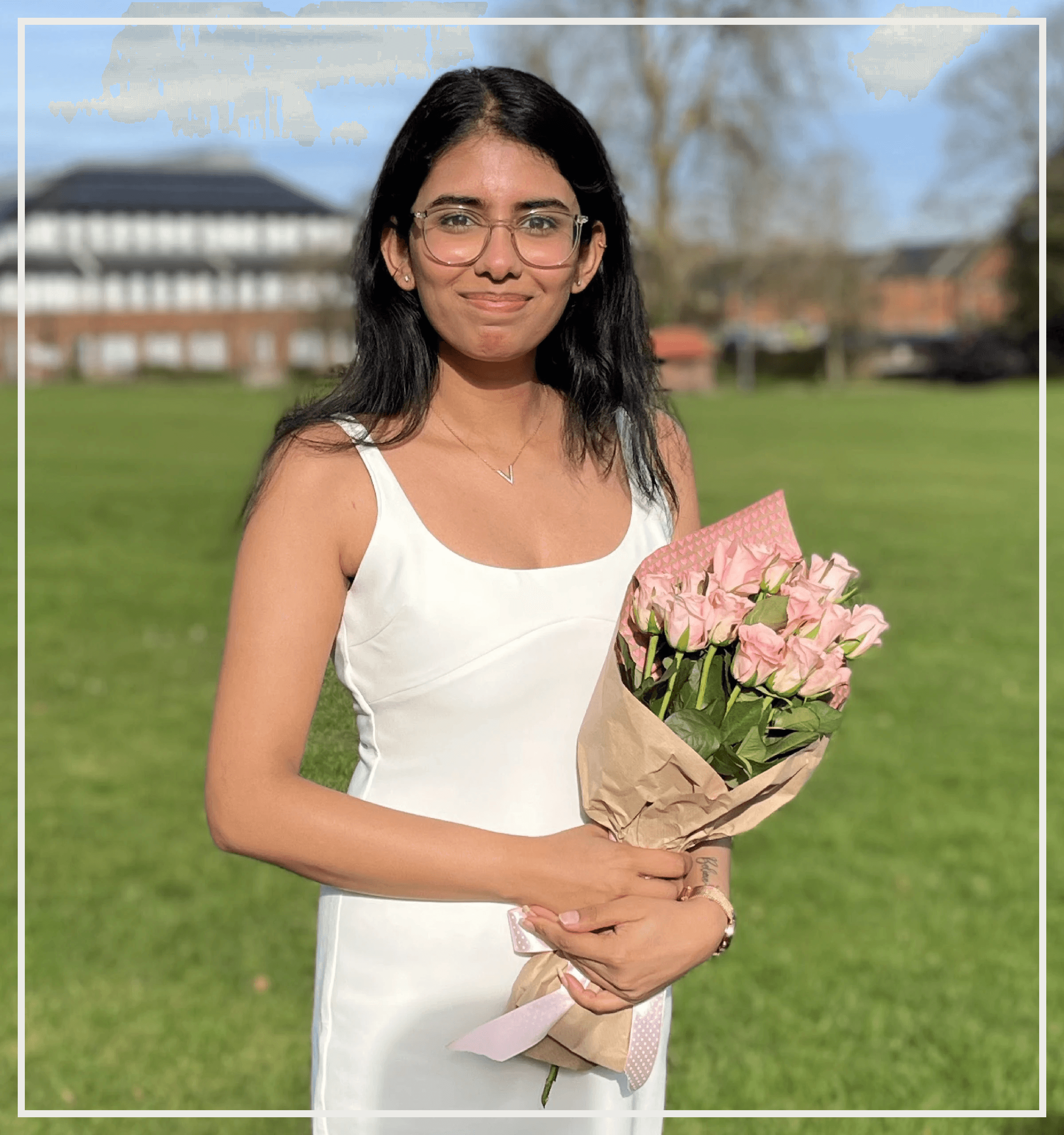 Picture of Vrinda in a white dress, standing in a scenic park holding flowers. The warm, natural setting reflects tranquility and connection with nature, embodying the essence of Healing Horizon's focus on holistic well-being.