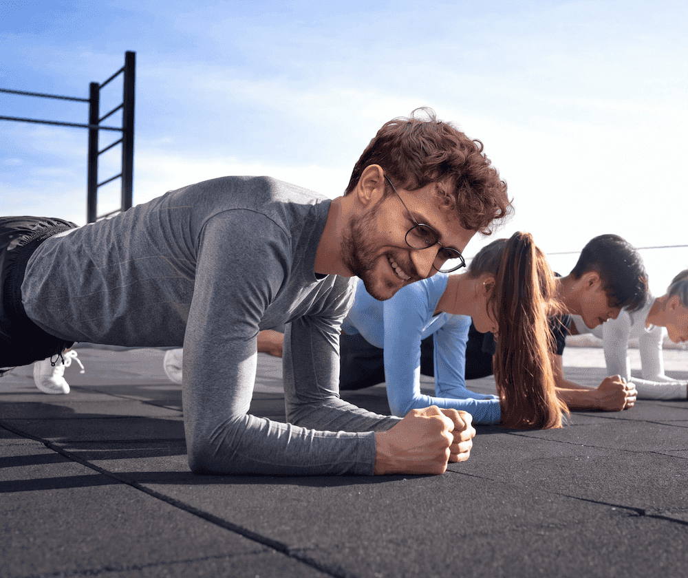 Gruppe von Mitarbeitenden im Plank beim Firmentraining im Freien