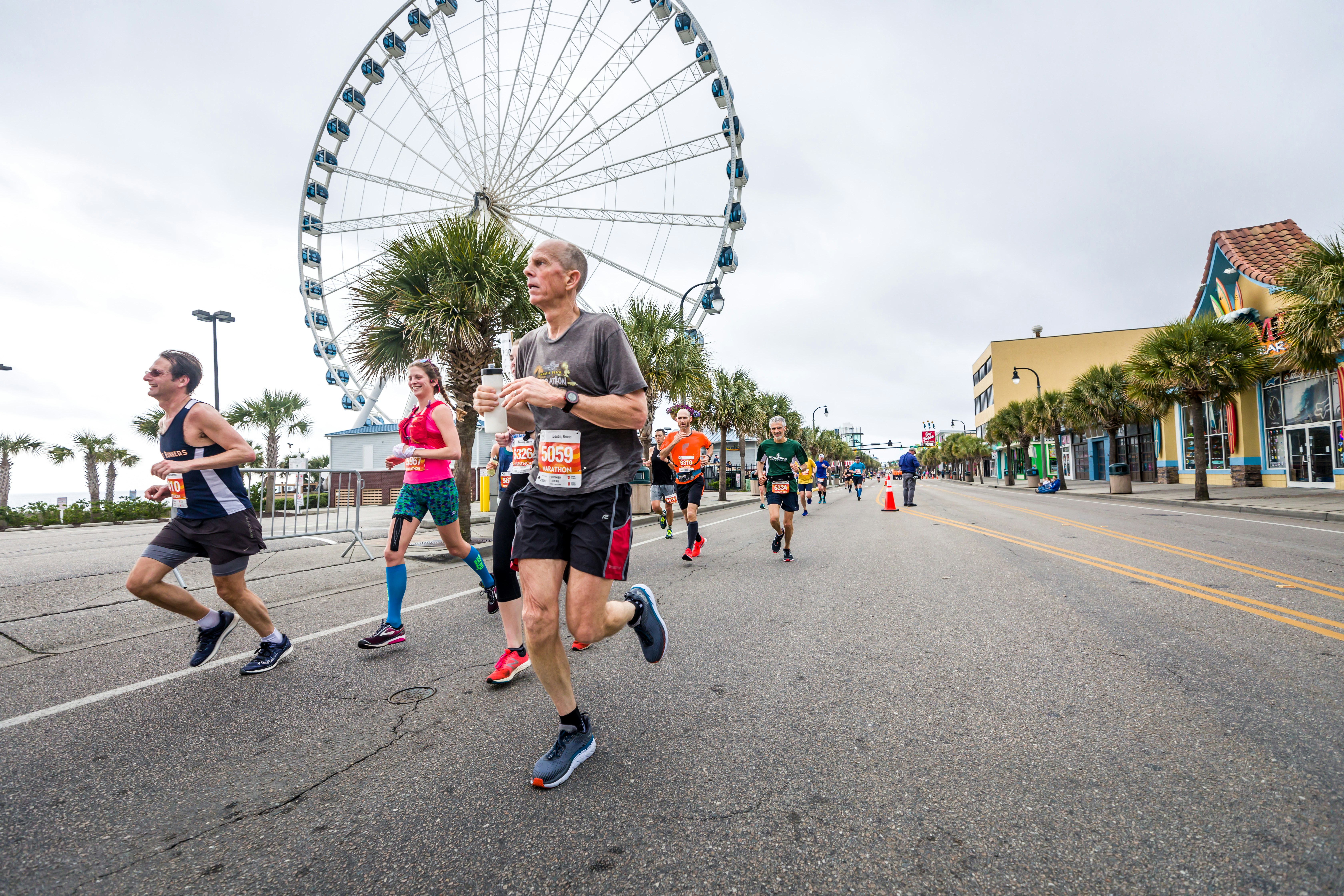 People Running Across a Big Avenue with a Ferriss Wheel Behind