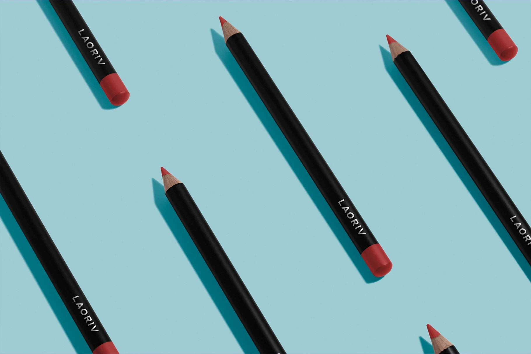 Cosmetic pencil mockup with red tips in a pattern on a light blue background.