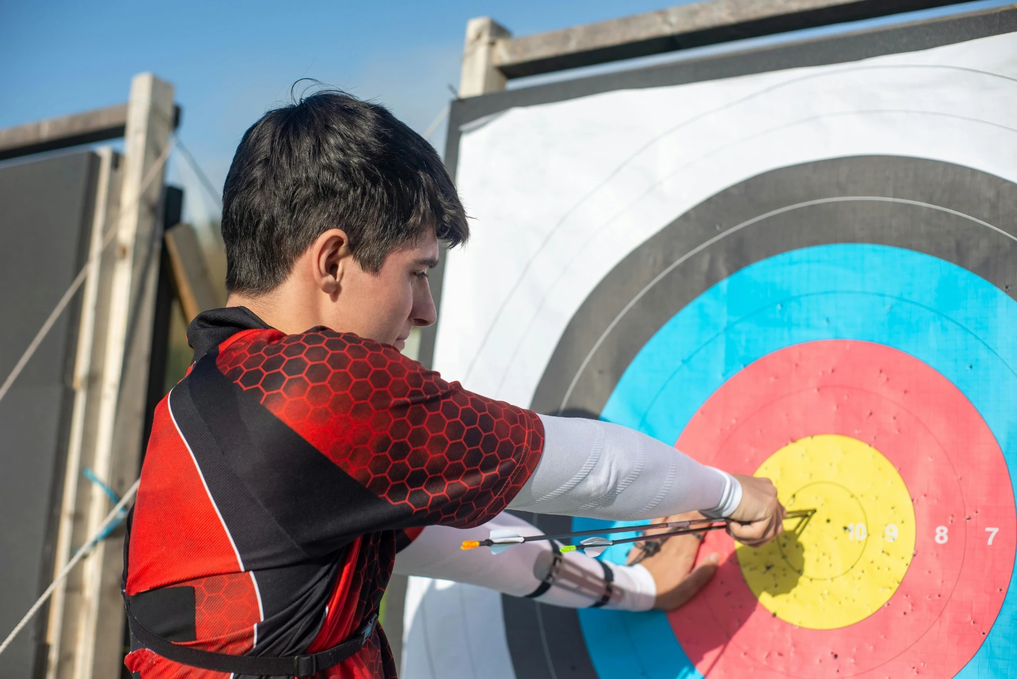 A young boy prepares to shoot an arrow at a vibrant archery target, showcasing his concentration and skill.