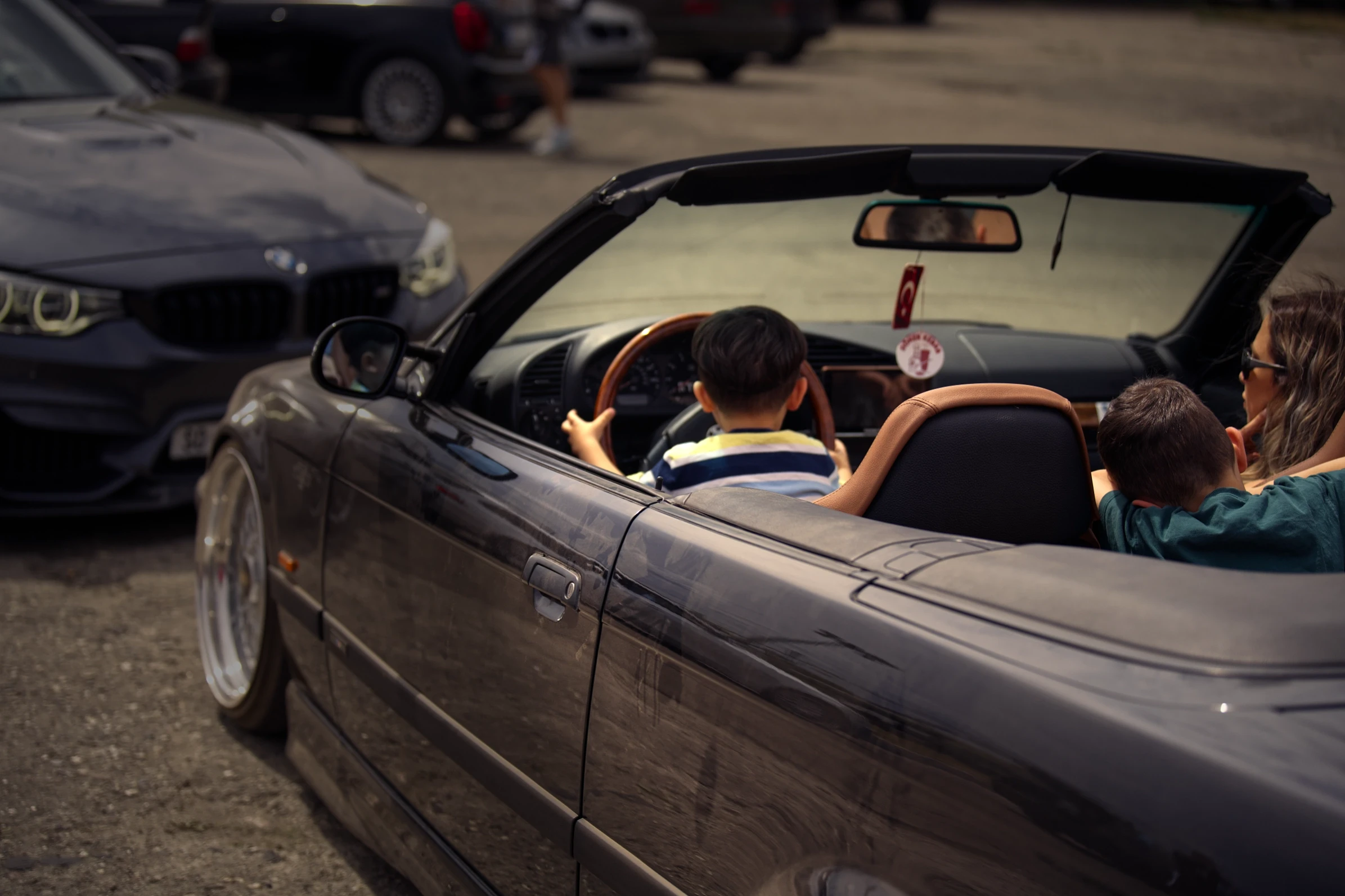 Kind am Steuer eines BMW E46 Cabriolets beim BMW Syndikat Asphaltfieber 2025 – familiäre Atmosphäre und generationsübergreifende Leidenschaft.
