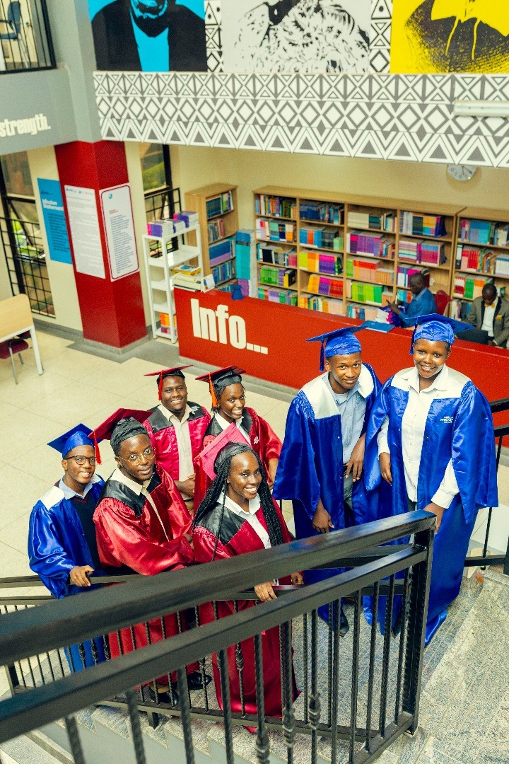 A teacher stands in the middle of the classroom between the desks