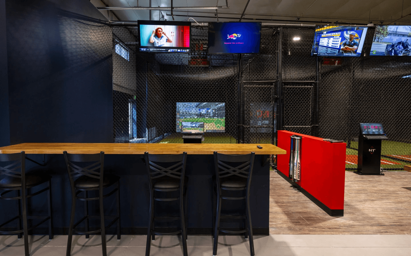 HitTrax Suite lounge area with bar-height counter seating facing the netted batting cage.