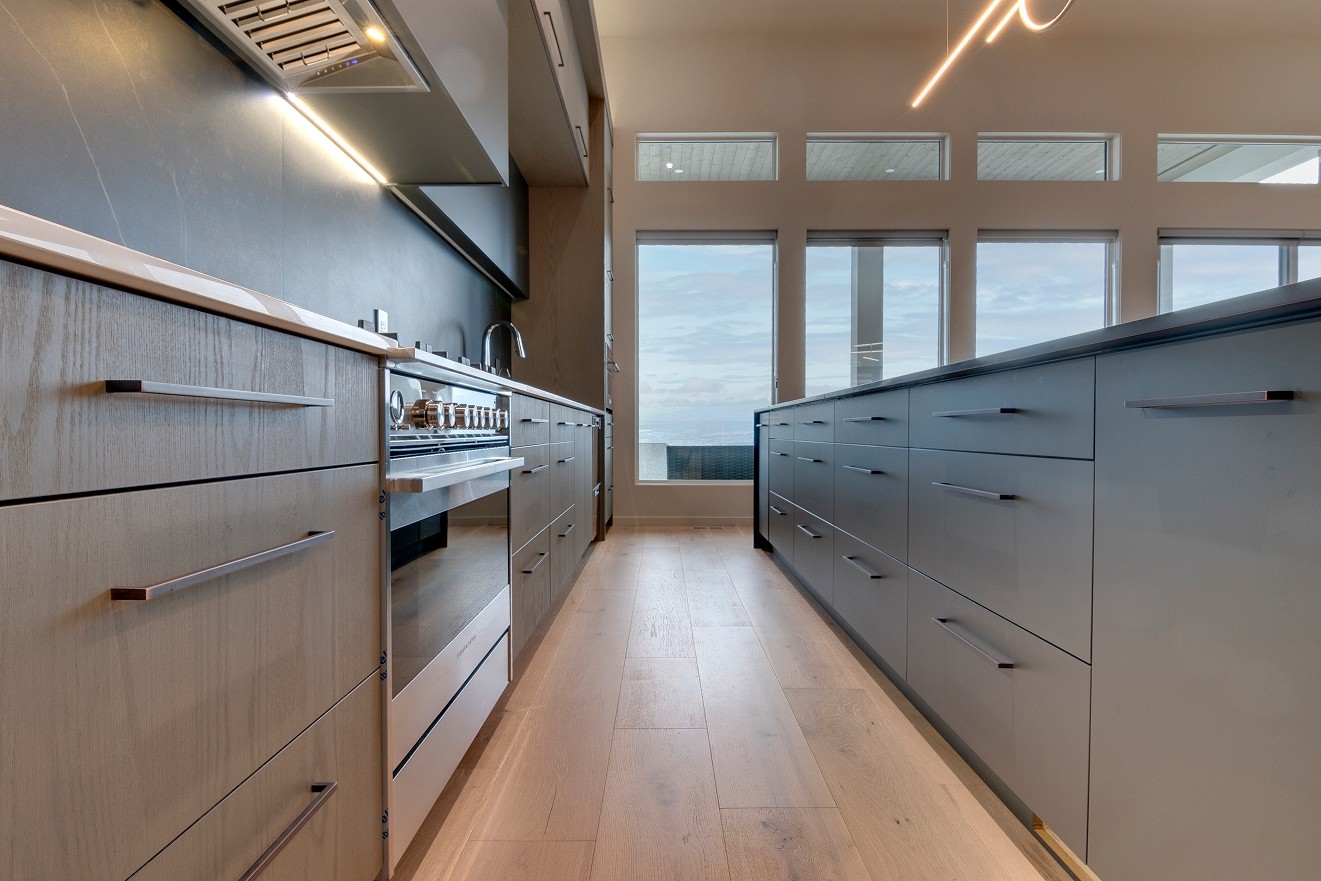 Long kitchen island with matte drawers and wood flooring