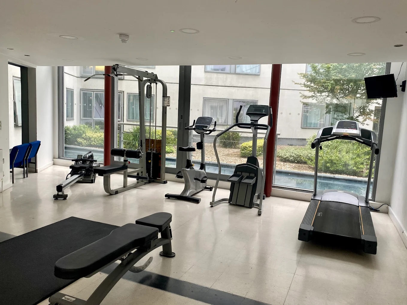 Luxurious modern house with a glass wall revealing a cozy living room, overlooking a pool and skyline. Warm sunset tones create an elegant ambiance.