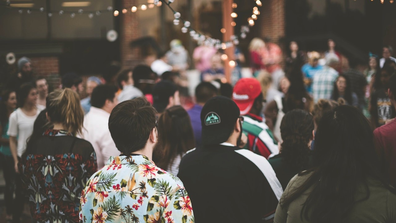 People mingling at a social event under string lights perfect for meeting new connections | Photo by Samantha Gades on Unsplash