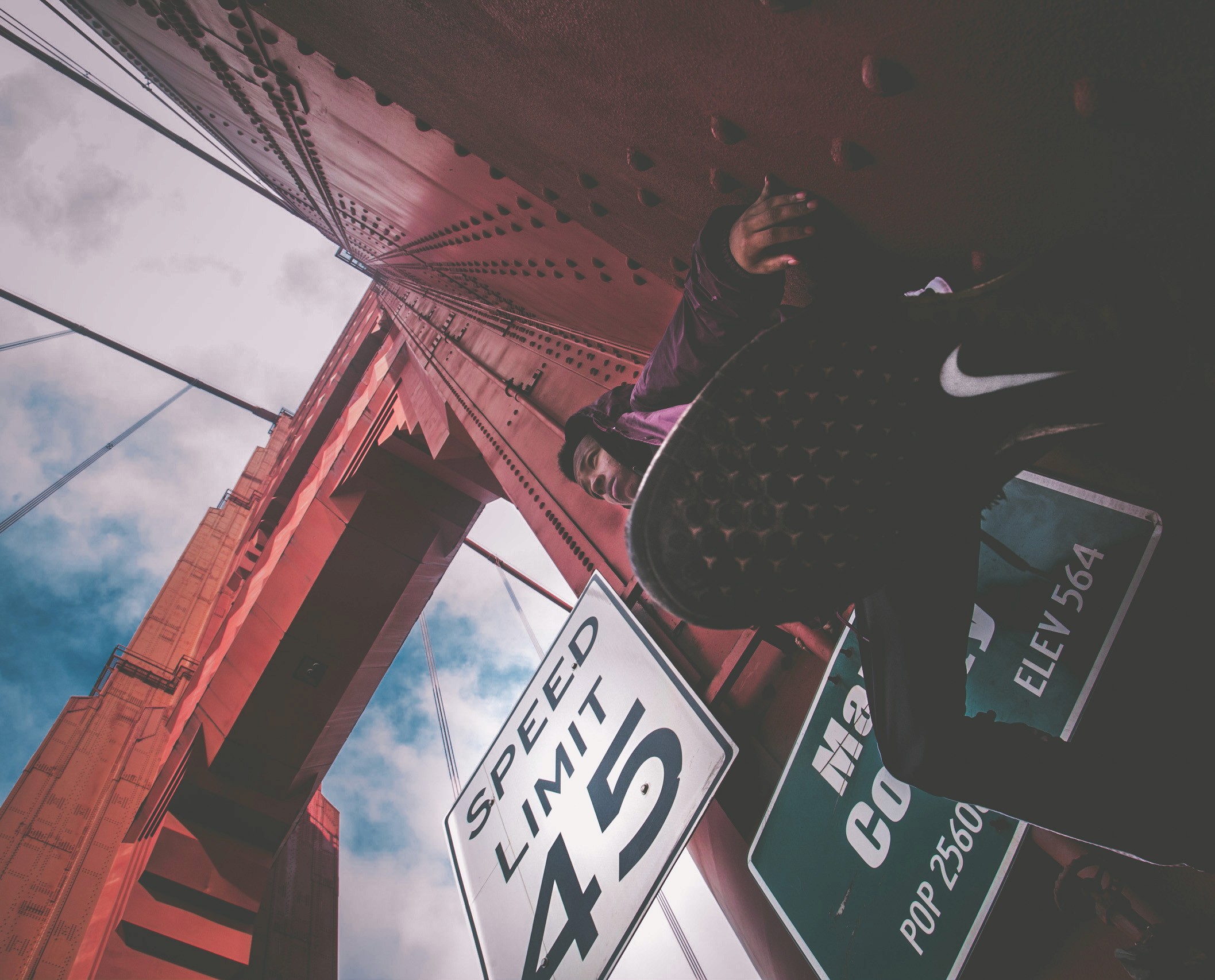 Photo from below of a man climbing on the Golden Gate Bridge