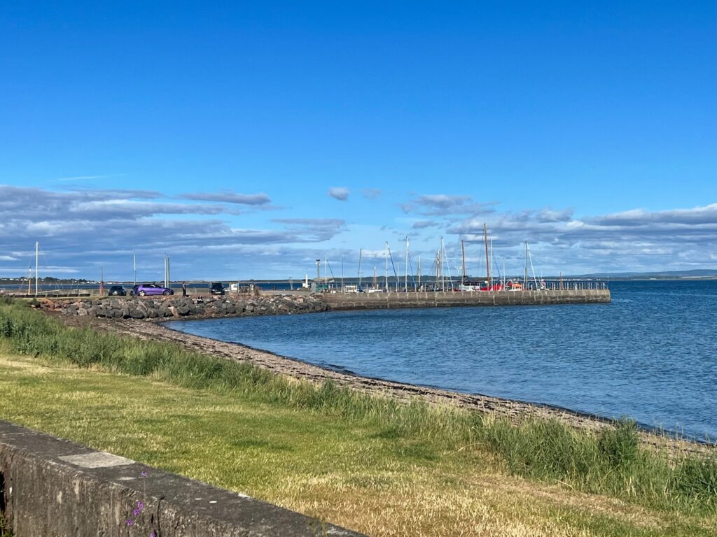 Avoch harbour in Scotland with the view of the sea and clear blue skies.