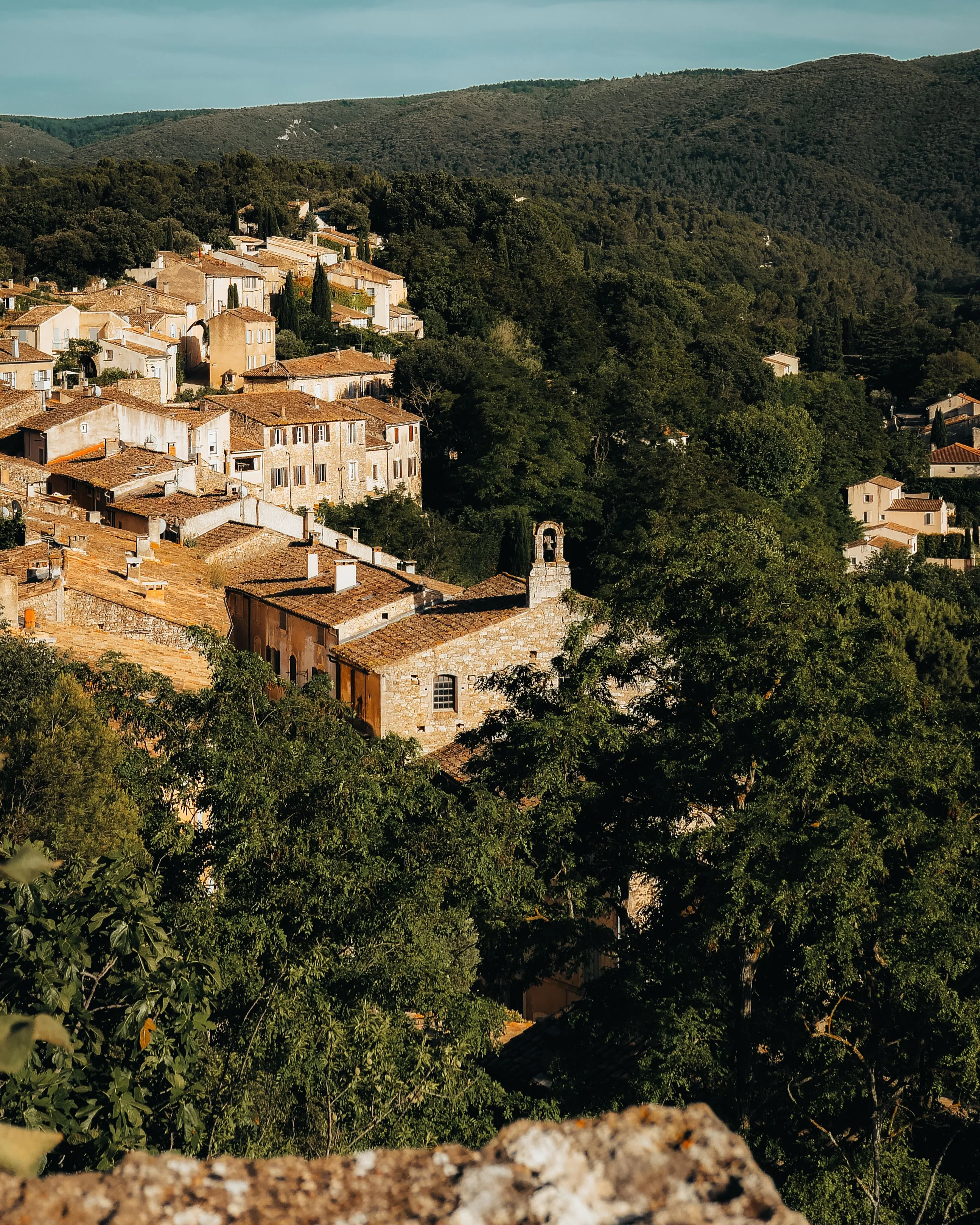 Stone village houses with terracotta roofs on a wooded hillside in Provence