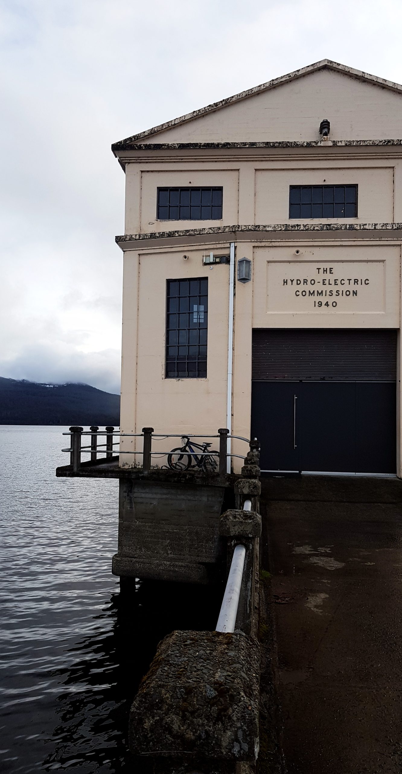 Facade of the Hydro-Electric Commission building reading "The Hydro-Electric Commission 1940", with a bicycle parked by the door