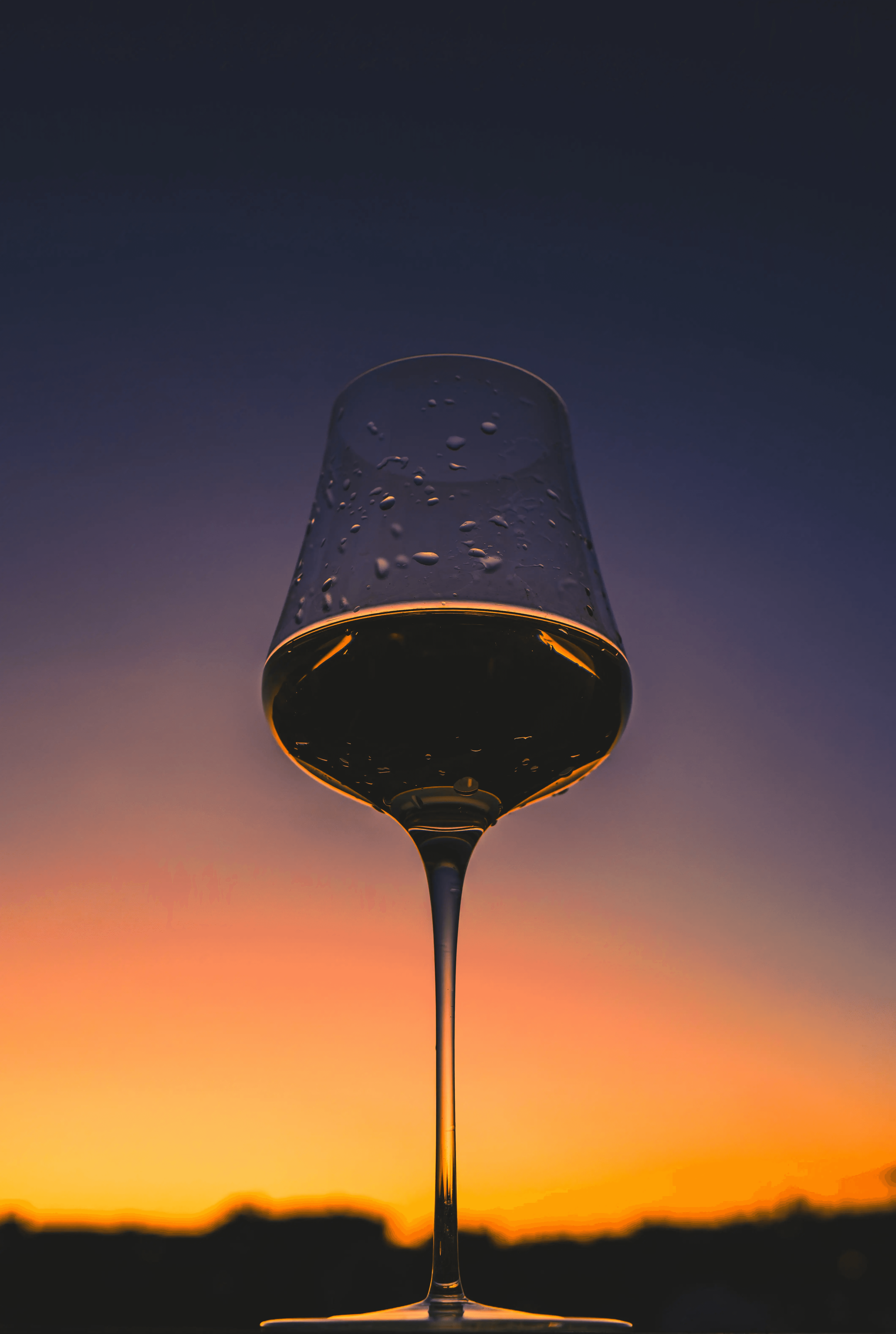 verre de vin avec un couché de soleil en arrière plan.