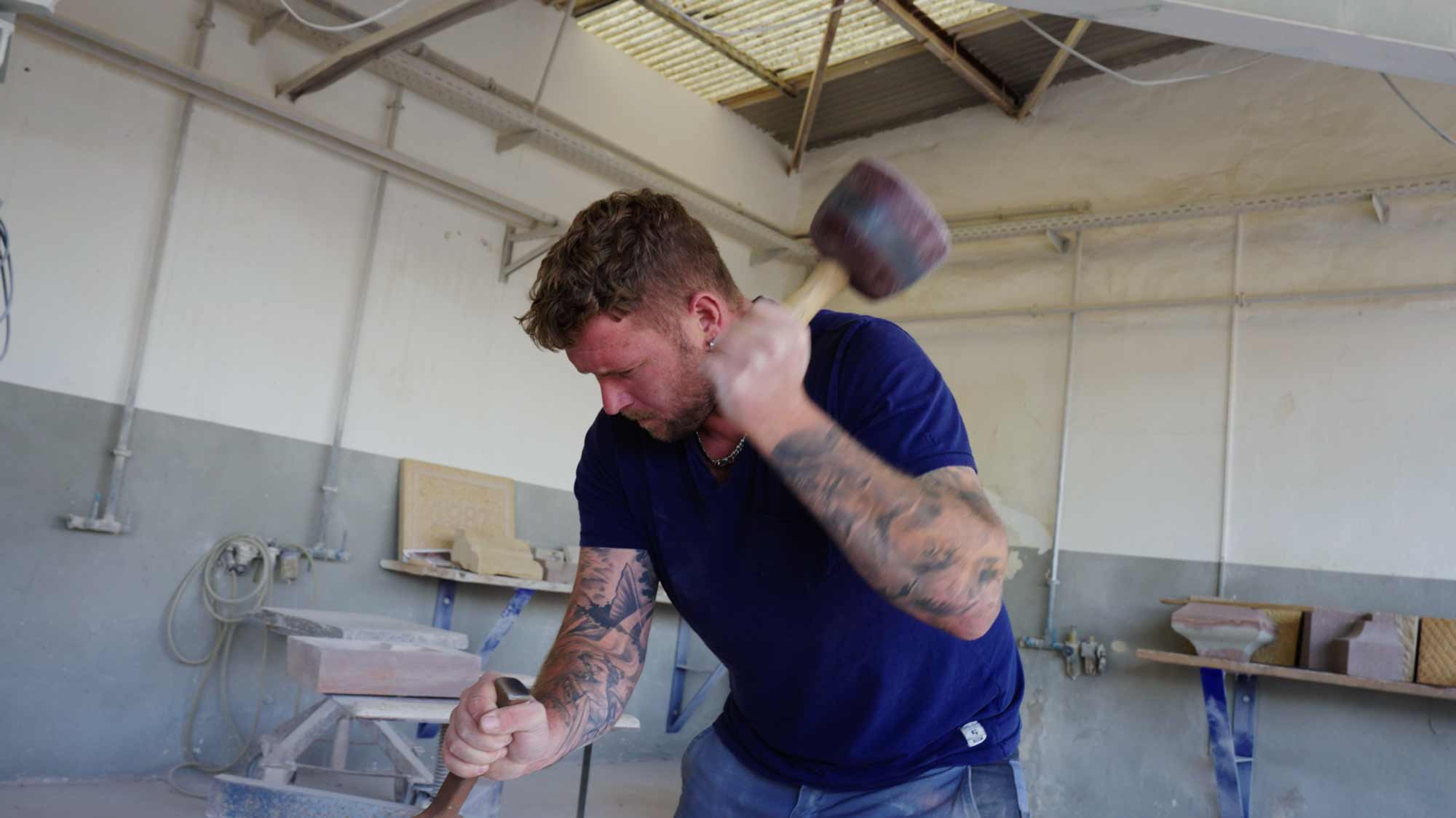 Man chiseling stone in workshop; strategic film production for ads, storytelling, and brand communication campaigns.