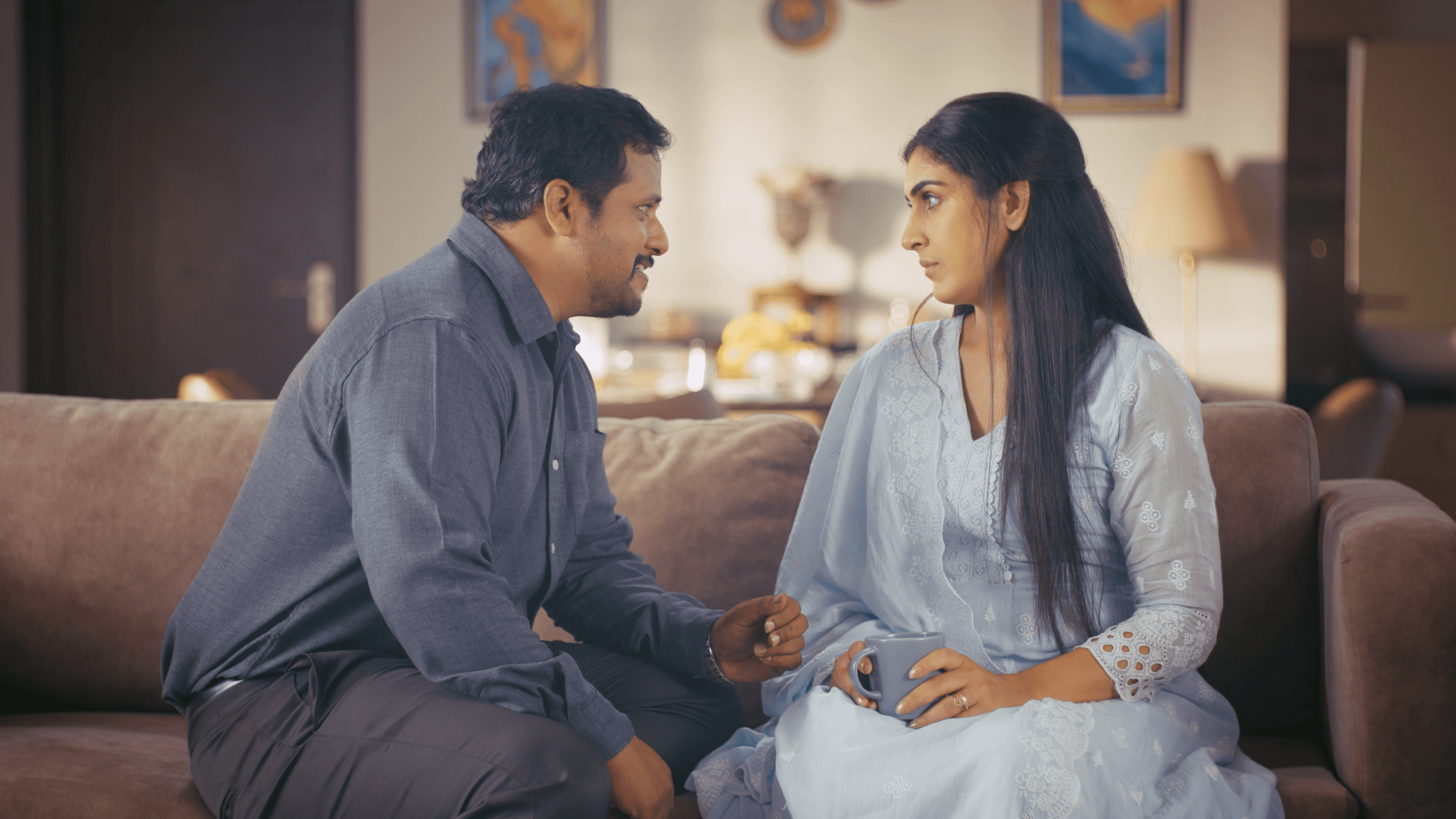 Couple in conversation on a sofa in an ad film for Hungersate.
