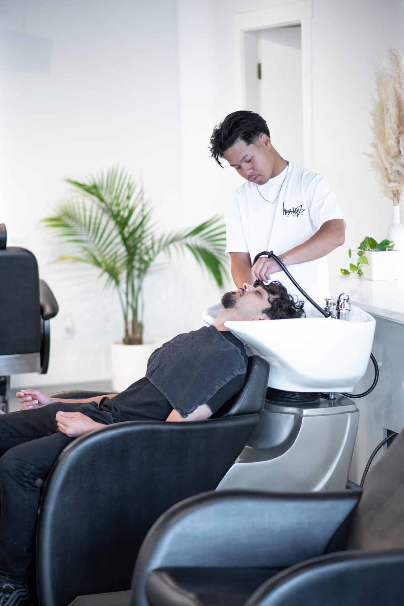Close-up of a golfer’s hand holding a golf ball, wearing a green-striped watch and white shirt with green shorts.