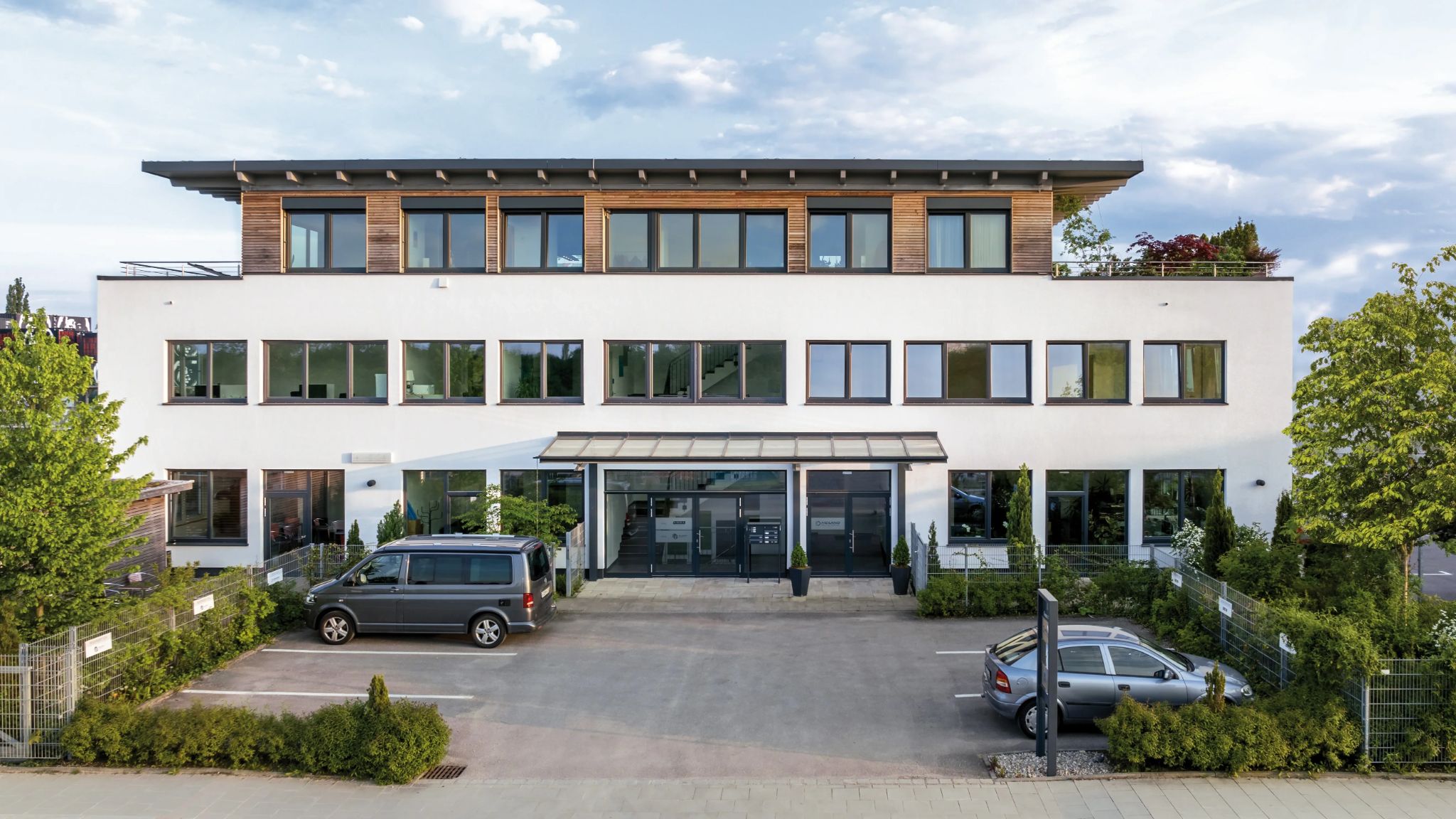 Blick auf modernes Bürogebäude mit leeren Parkplätzen davor.