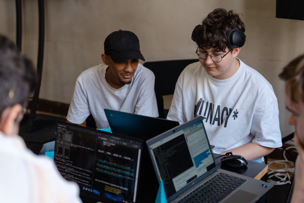 Two developers collaborating on laptops during a coding session at Evolve 26 Brighton