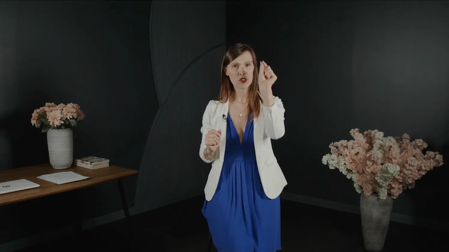 Femme debout face caméra dans un studio, guidant un exercice pour transformer ses pensées limitantes