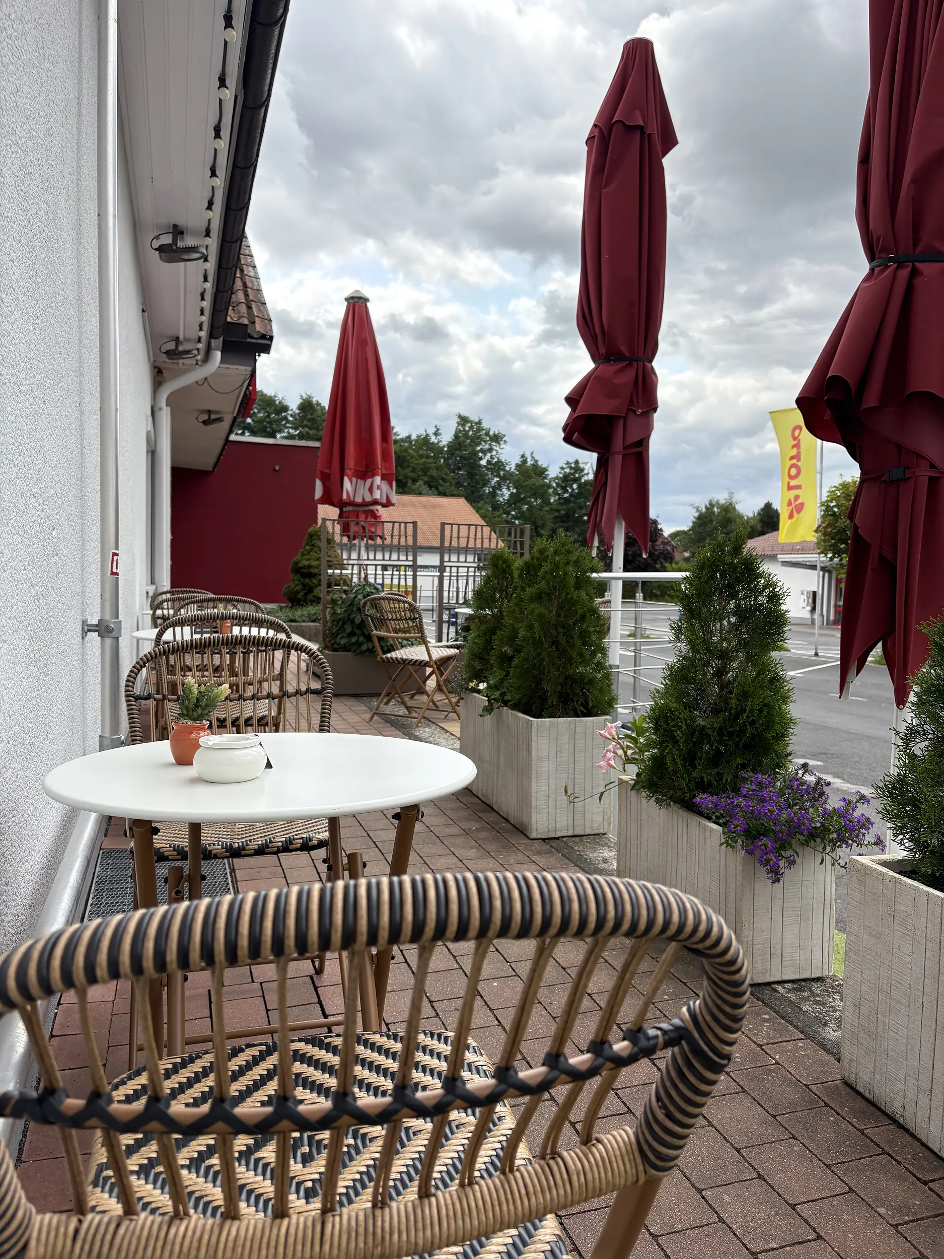 Außenterrasse des Eiscafés mit Tischen und Sonnenschirmen