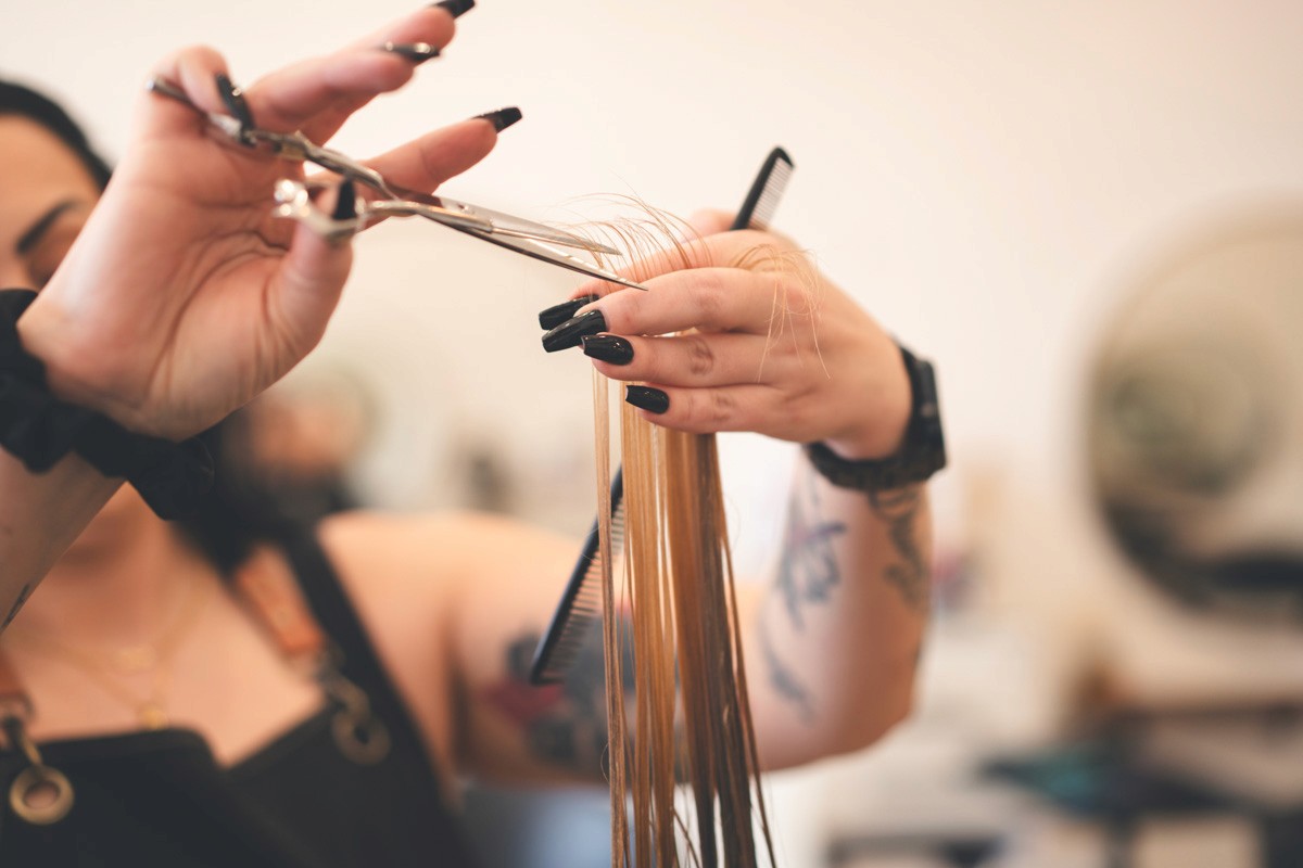 Close-up of a hairstylist cutting blonde hair with shears, mid-service, showcasing precision and technique in the salon.