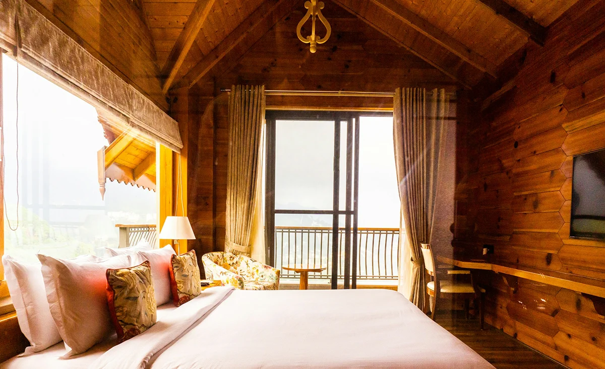 Beachfront bungalow with a warm wooden interior, queen bed, and balcony facing the ocean.