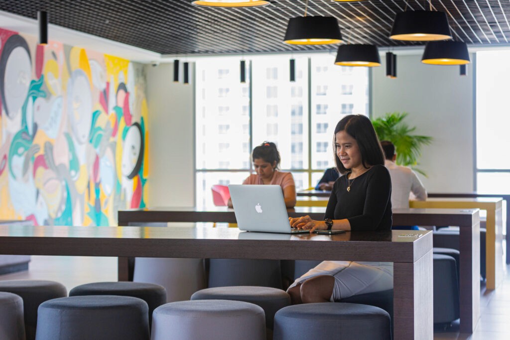 A woman working in a relaxed setting at a coworking lounge in myOffice. 