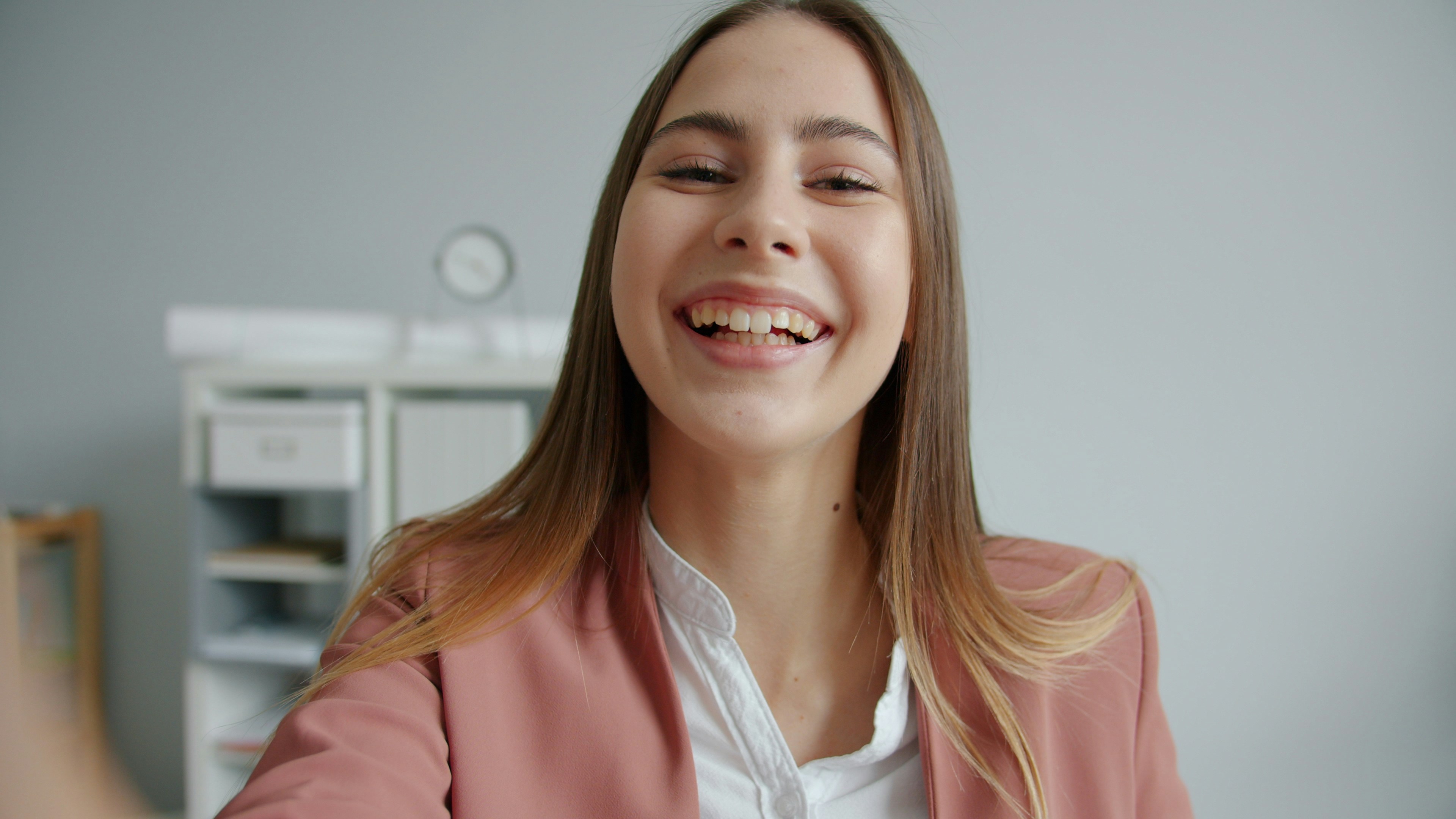 A smiling young woman in a pink blazer