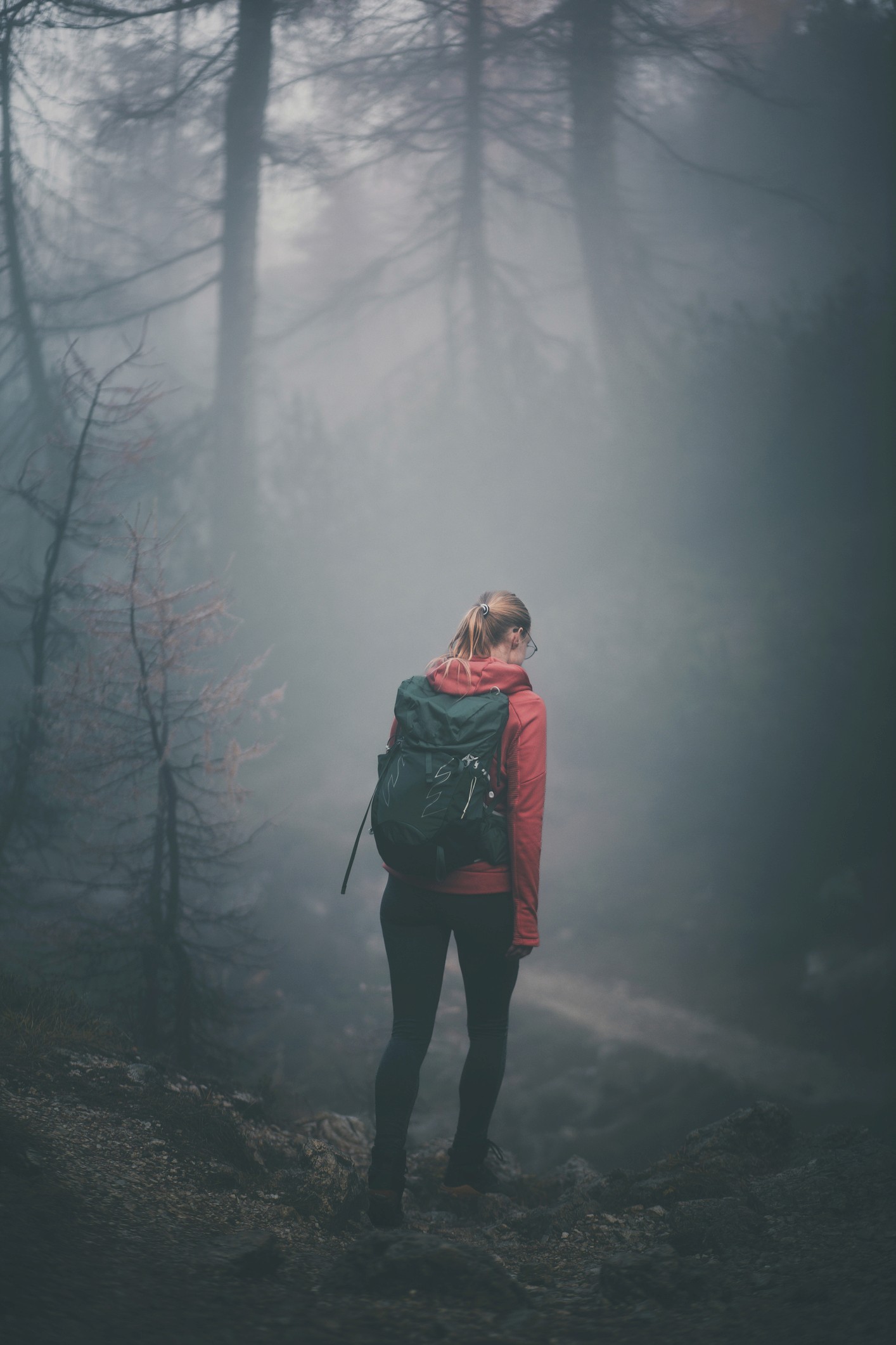 Smiling young man with short hair poses against a dark background, wearing a green button-up shirt.