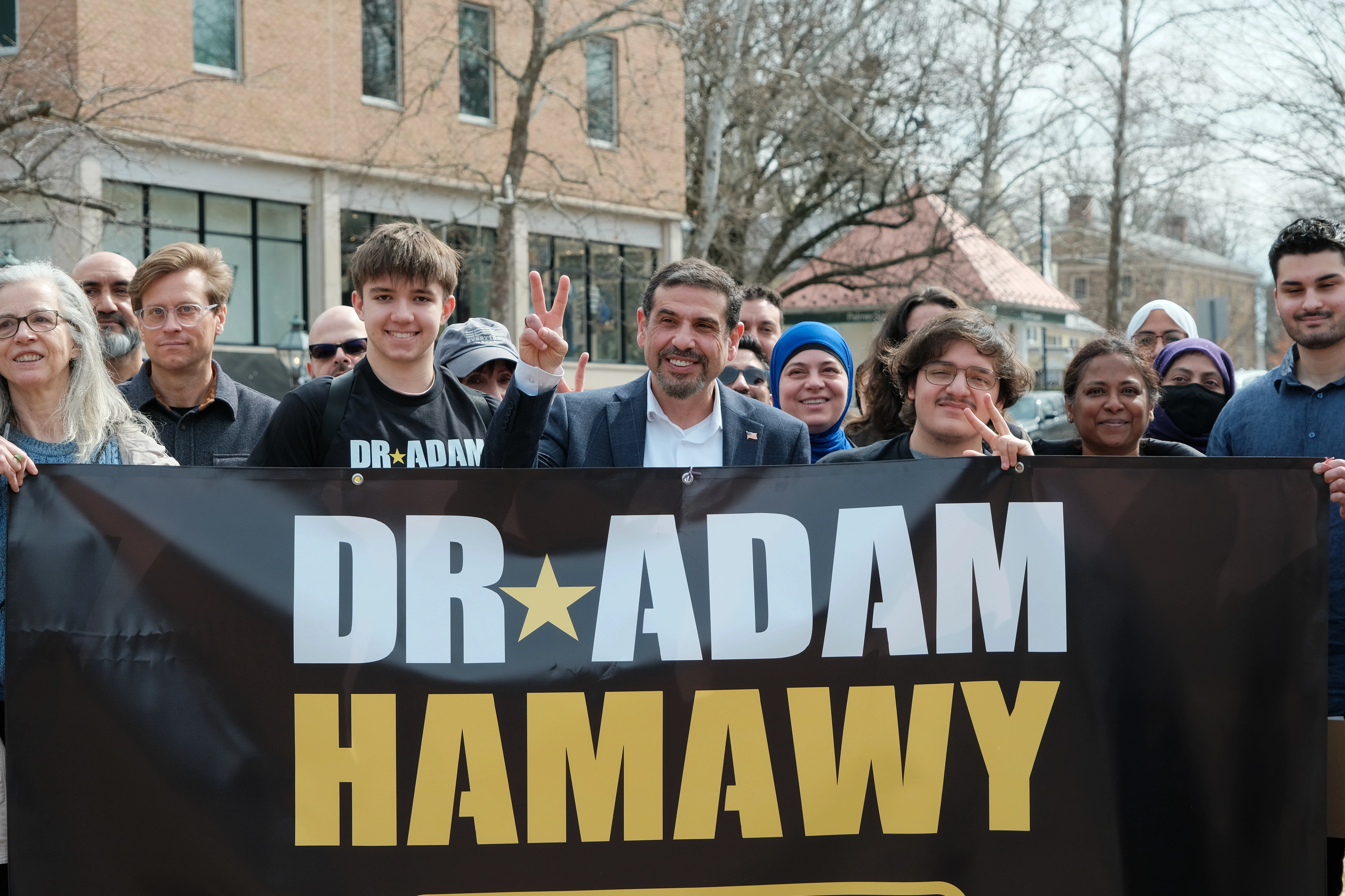 Dr. Adam Hamawy with supporters holding campaign banner at community rally in New Jersey District 12