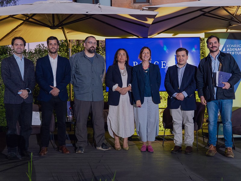 Personas del público leyendo atentamente la edición número 9 y especial 15 años de la Revista Raíces durante su evento de lanzamiento de IdeaPaís.