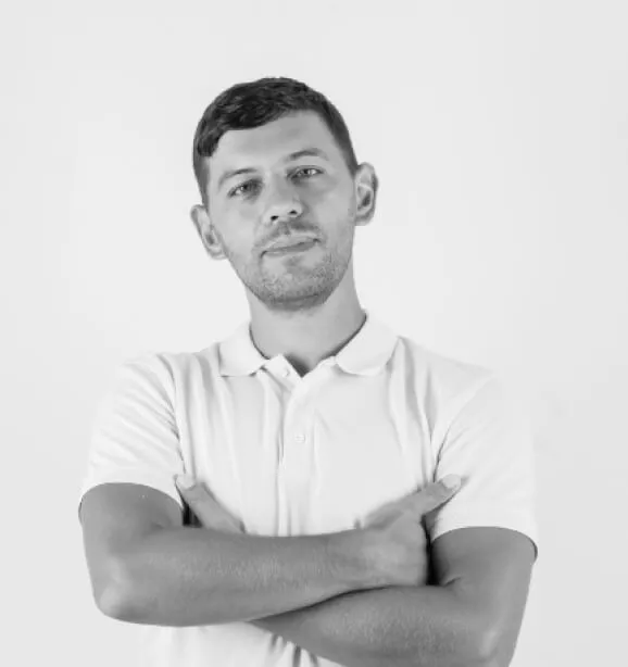 Portrait of a man with short hair, wearing a light polo shirt with arms crossed, standing against a plain background