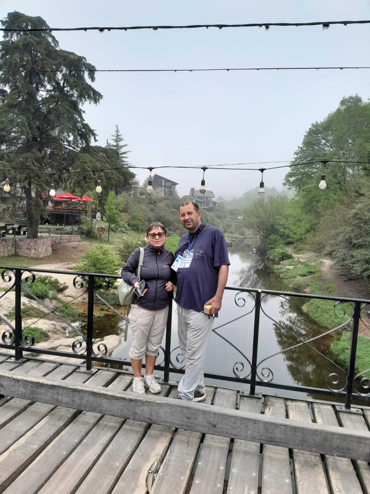 Mujer sentada sobre un tronco frente a una cascada doble en un bosque frondoso de Argentina.