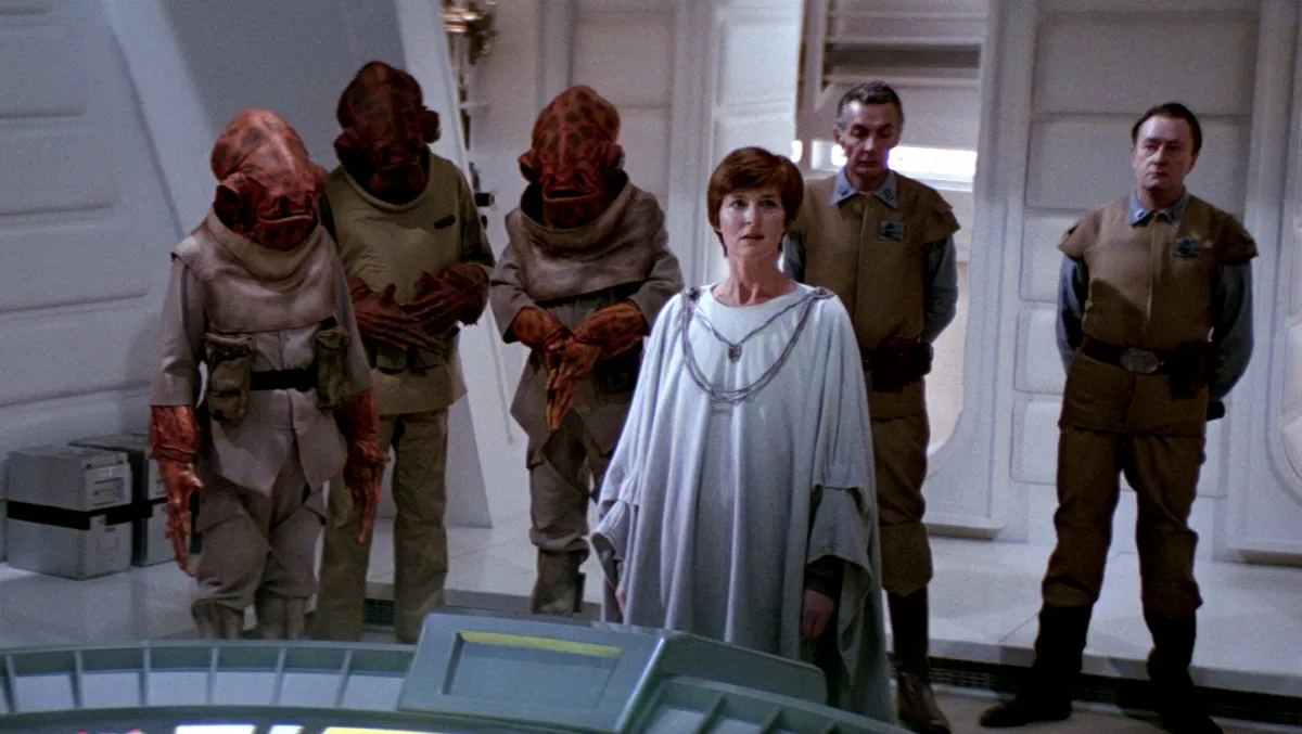 Mon Mothma stands at the center of a Rebel Alliance war room, surrounded by Mon Calamari officers and military personnel as they prepare for battle.