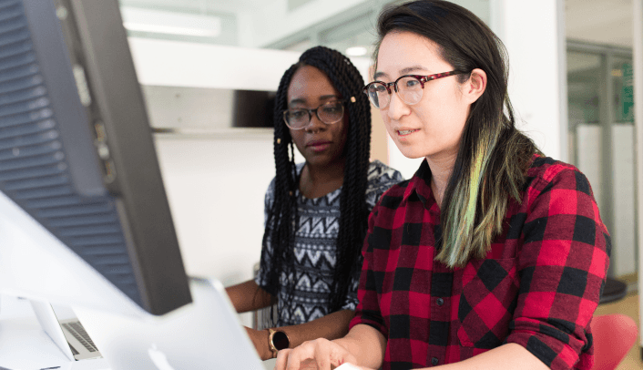 Two colleagues working together at a computer in an office.