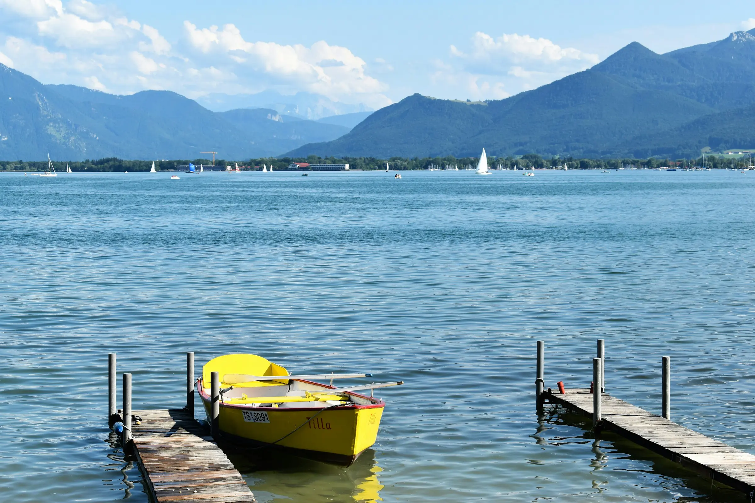 Chiemsee bei Prien, Steg mit gelbem Ruderboot vor den Chiemgauer Alpen
