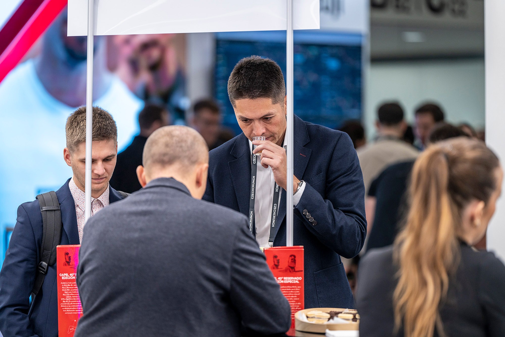 Attendees networking and tasting samples at exhibitor stand during the Money Maker business conference by CzechCrunch in Prague.